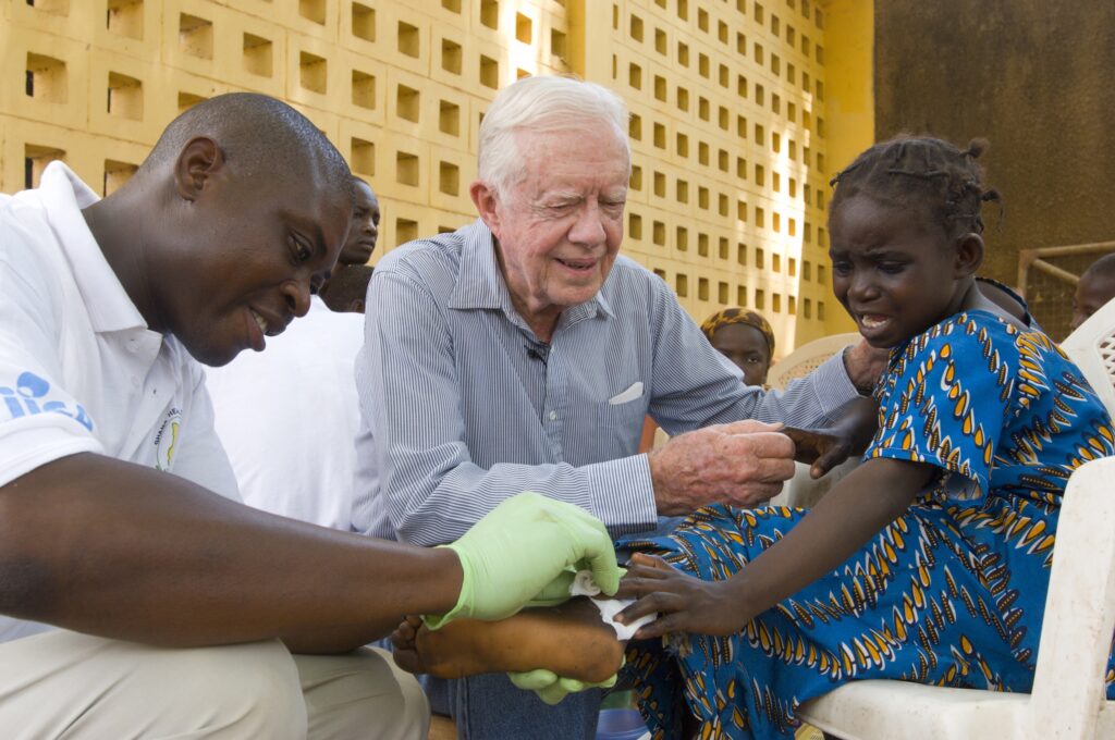 Jimmy Carter tries to comfort 6-year-old girl at Savelugu Hospital in Ghana as Carter Center assistant dresses her extremely painful Guinea worm wound 2007 credit: The Carter Center